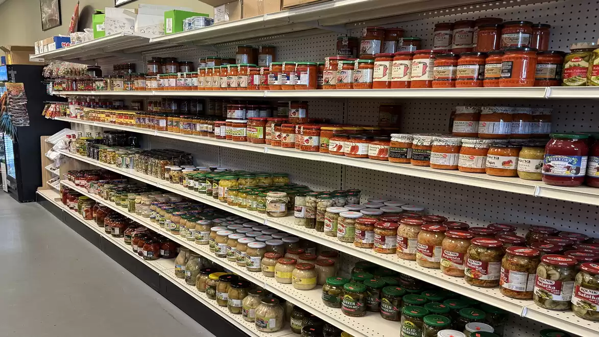 Shelves in a supermarket filled with canned foods and spices in jars and cans.