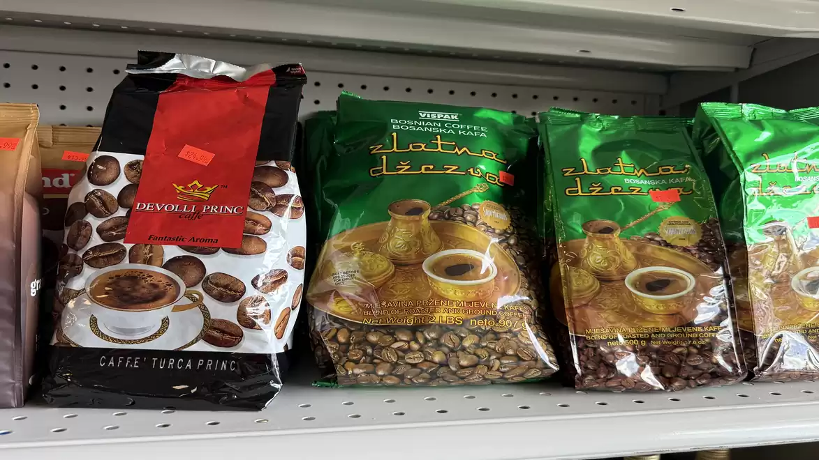 Various coffee packages on a supermarket shelf, including Caffe Turca and Zlatna Dzvezva with coffee bean images.