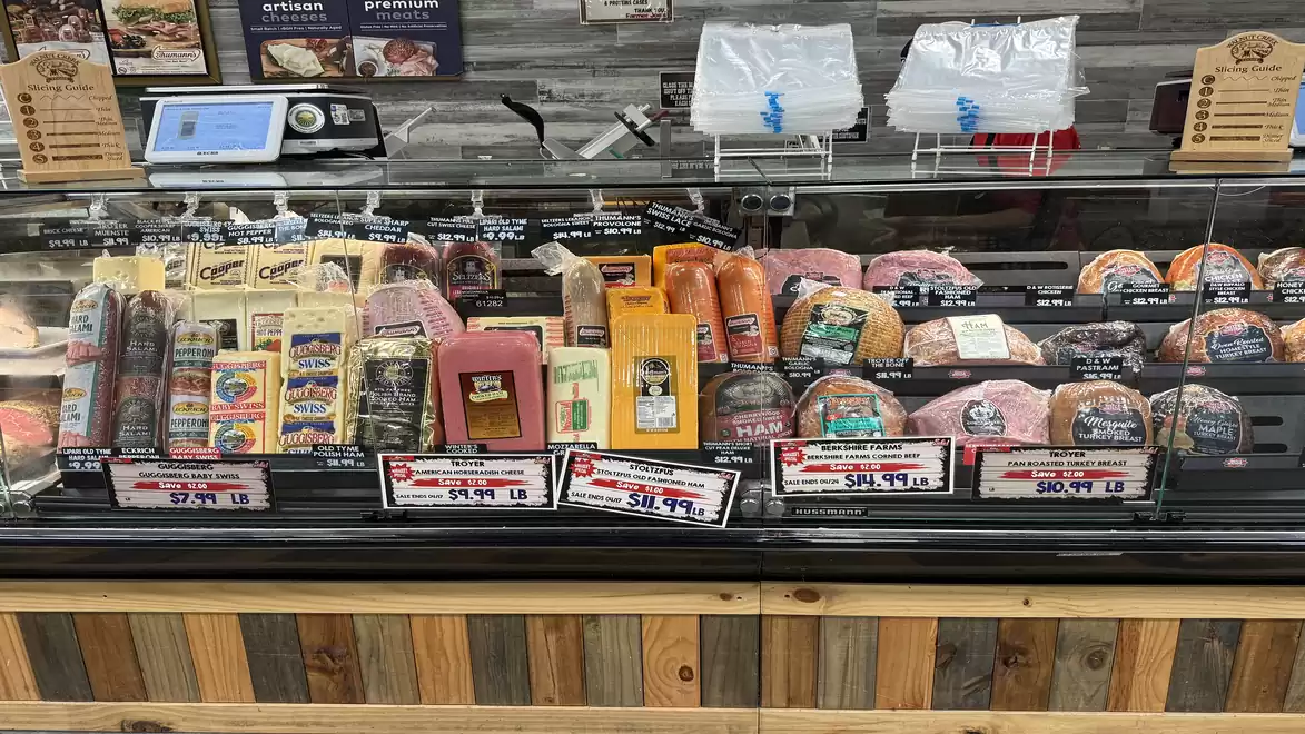 Cheese and meat counter in a supermarket with various products.