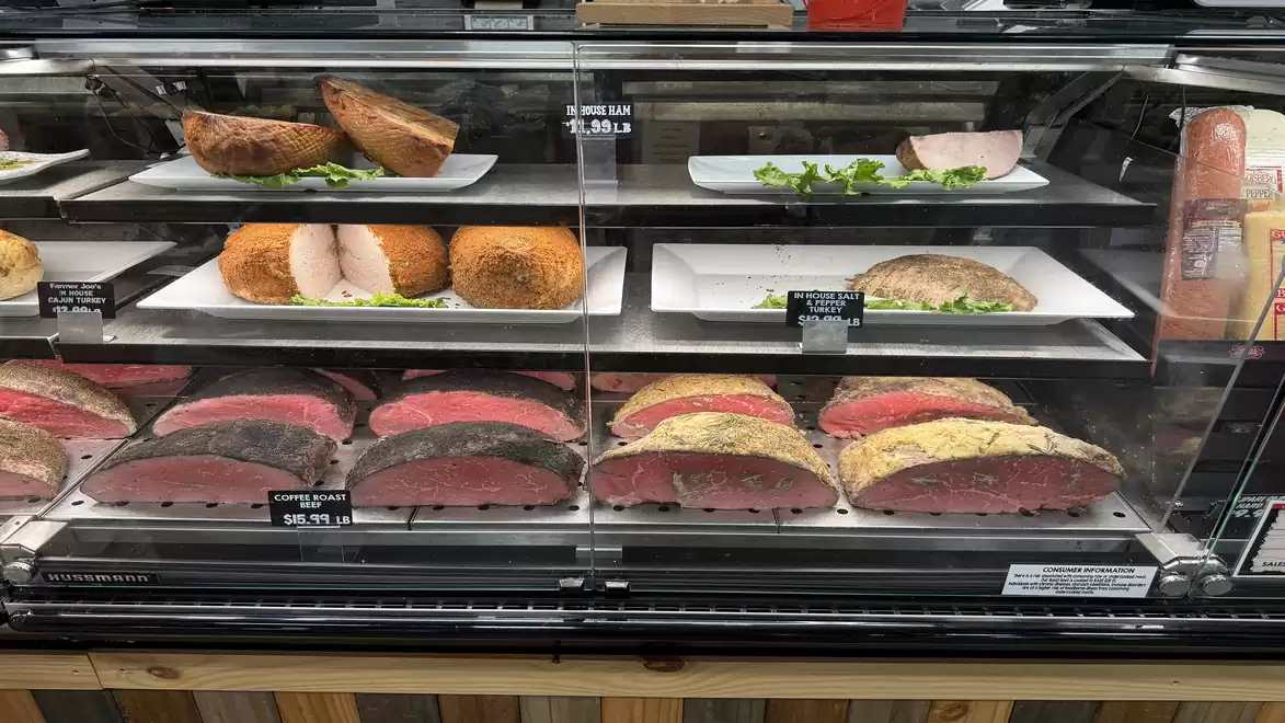 Deli showcase with various types of meat in a refrigerated display.