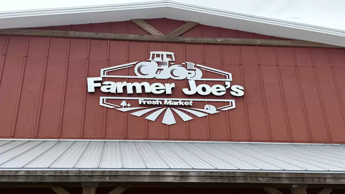 The image shows the sign of a building with the inscription 'Farmer Joe's Fresh Market' on a red wooden facade.