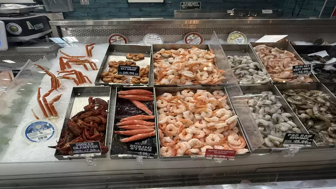 Fresh seafood display featuring crab legs, shrimp, and other seafood products in a supermarket.