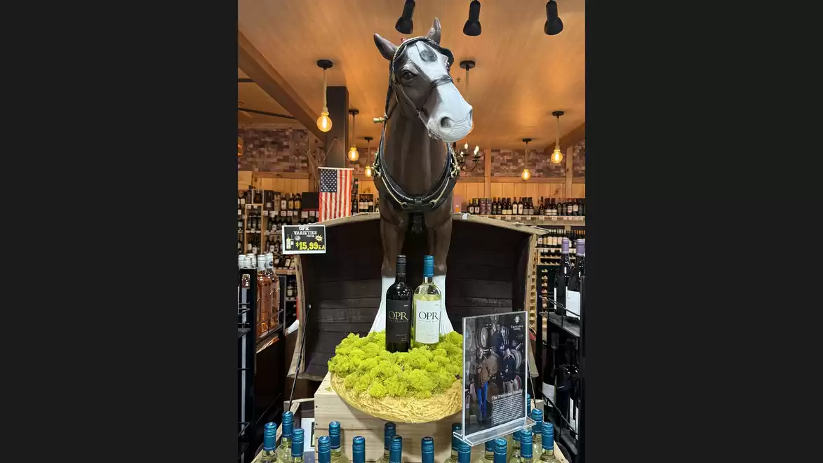 Horse statue in a wine shop, surrounded by bottles and decorative setting.