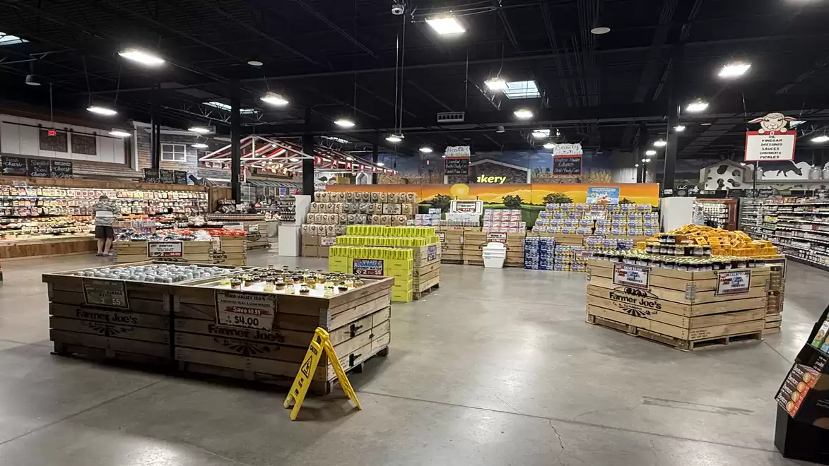 Large indoor space of a supermarket with wooden shelves and fruit and vegetable displays.