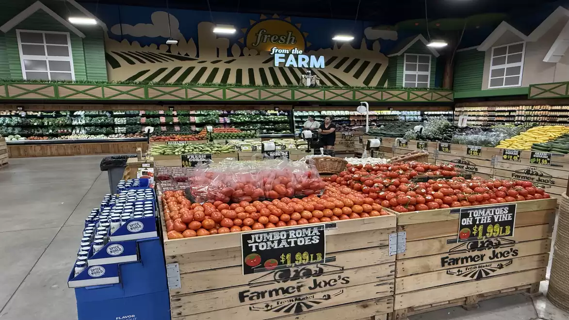 A supermarket displays a wide variety of fresh fruits and vegetables, with a special focus on tomatoes. A rustic decor with a sign that reads 'Fresh From the Farm'.