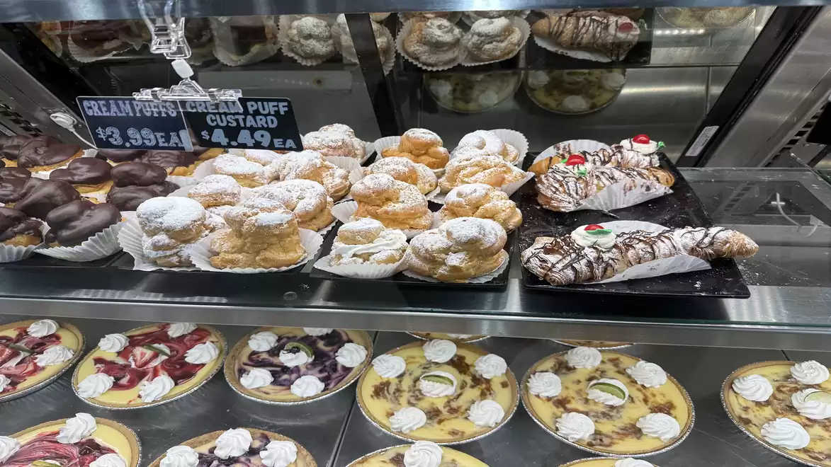Display case with various types of pastries including cream puffs and cakes.