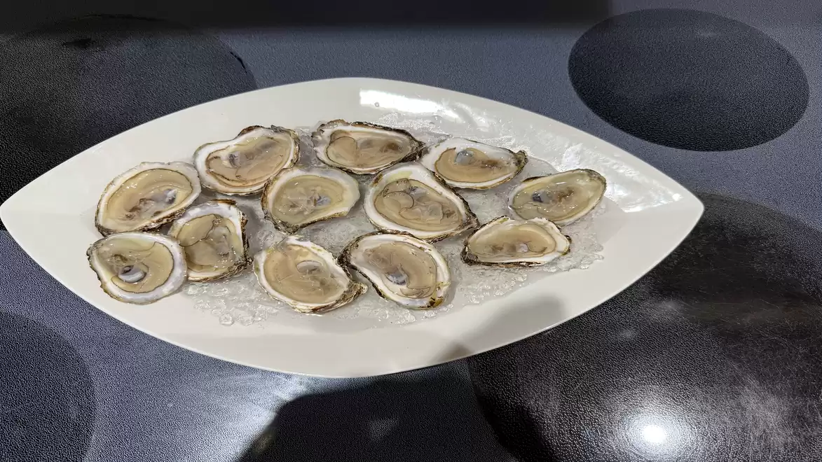 A plate of fresh oysters on a dark surface.