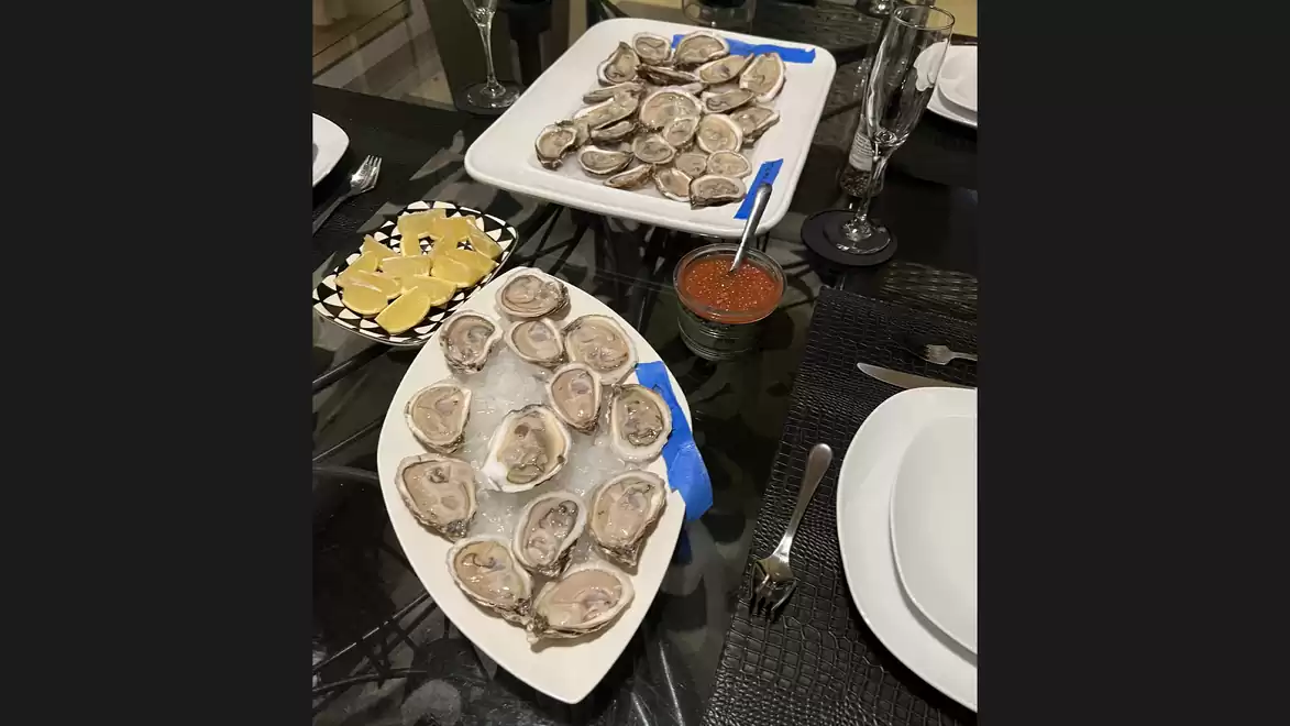 A set table with fresh oysters on ice, accompanied by lemon and cocktail sauce.