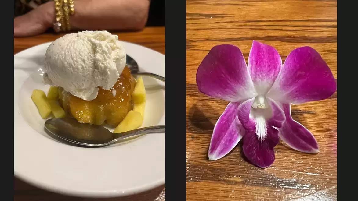 A dessert with pineapple and vanilla ice cream on the left side and a purple orchid flower on the right side.