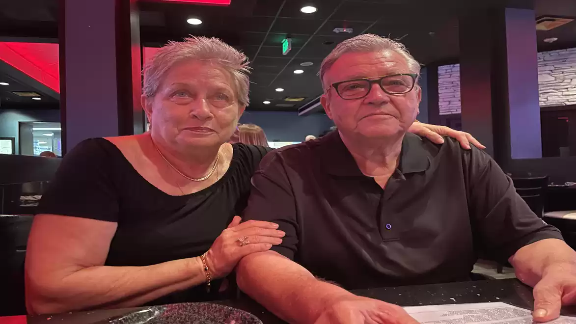 An elderly couple sitting together in a restaurant, enjoying the evening. They appear relaxed and happy.