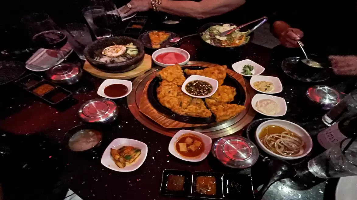 A set table full of Korean dishes including pancakes, sauces, and side dishes.