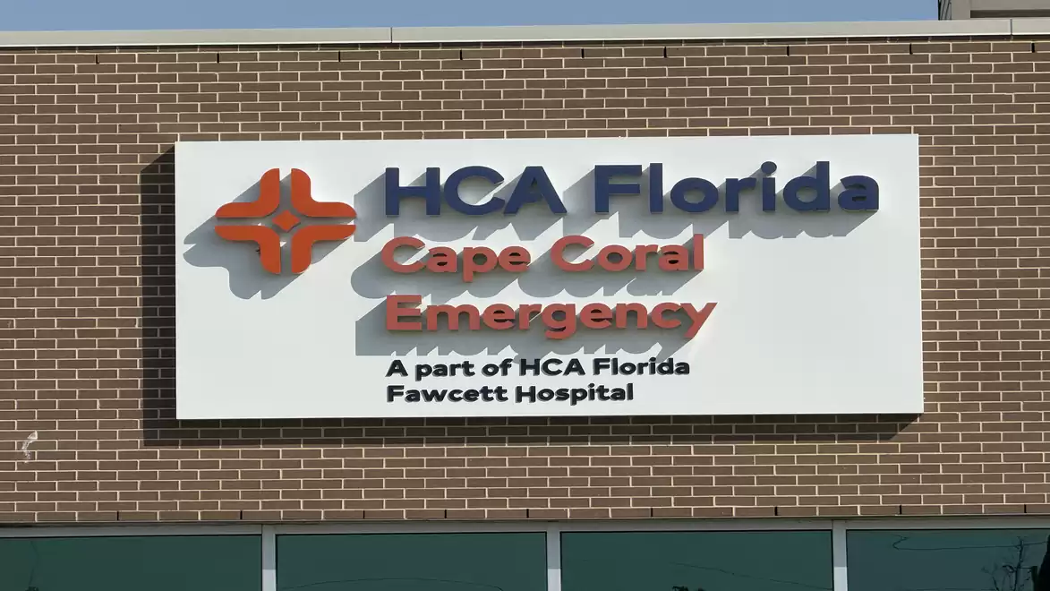 A sign on a building that reads 'HCA Florida Cape Coral Emergency', part of the HCA Florida Fawcett Hospital.