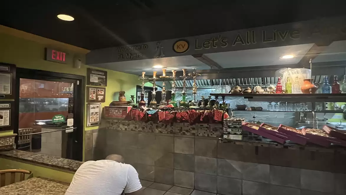 Interior view of a cozy restaurant with a counter, seating area, and decorative lighting.