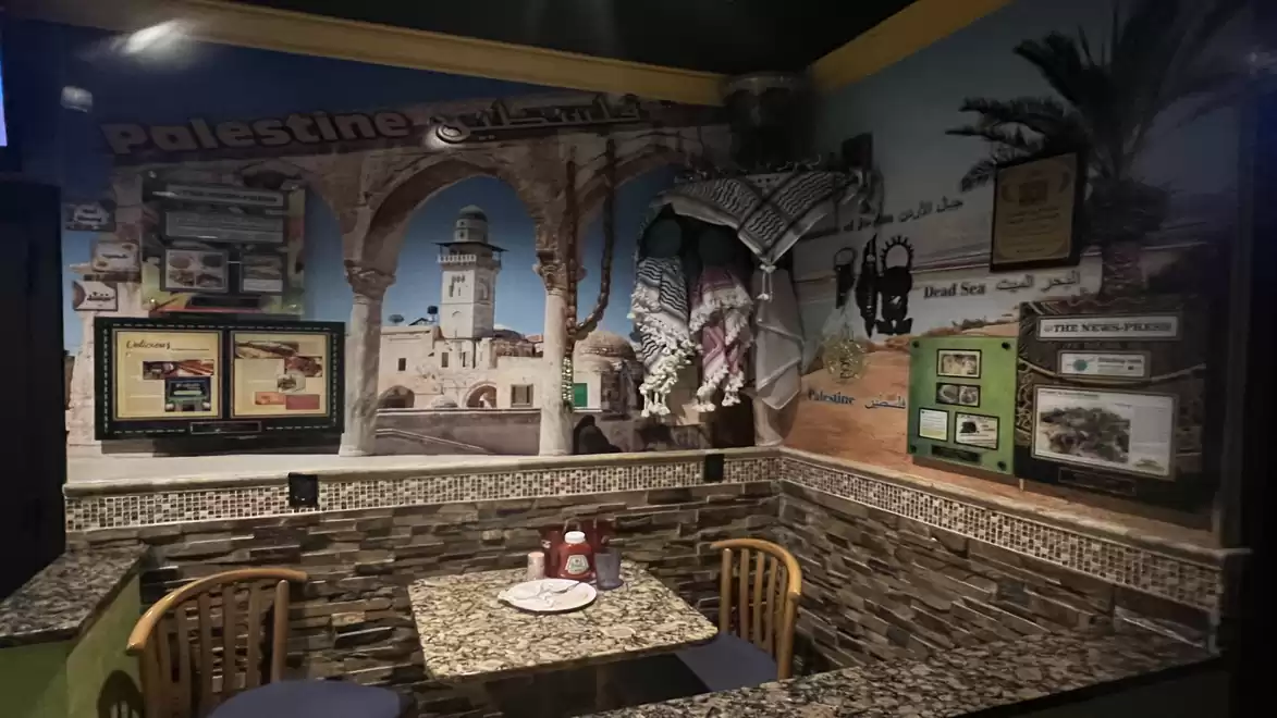 Interior of a themed restaurant with Palestine motifs, decorative wall paintings, and modern seating areas.