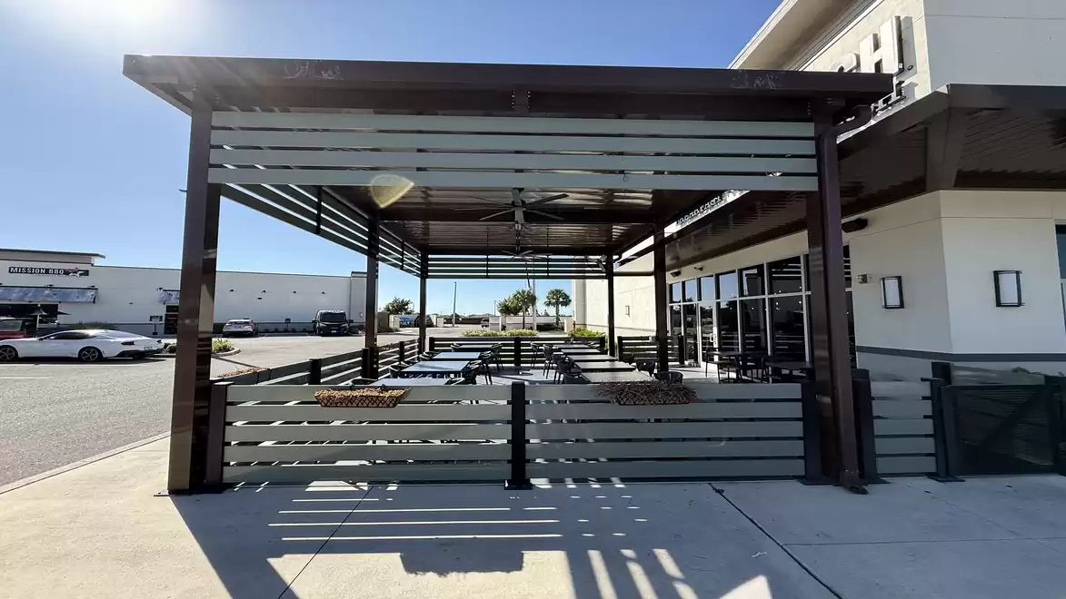 Outdoor seating area of a restaurant with a covered space on a sunny day.