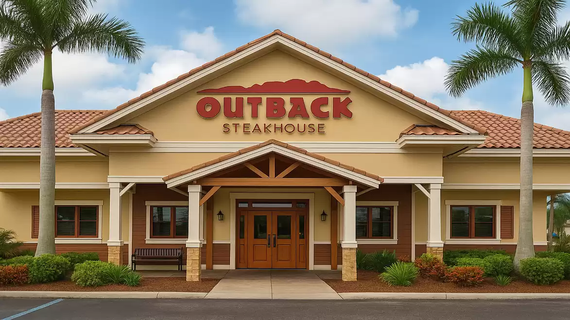 Front view of an Outback Steakhouse restaurant with palm trees in the foreground and clear sky.