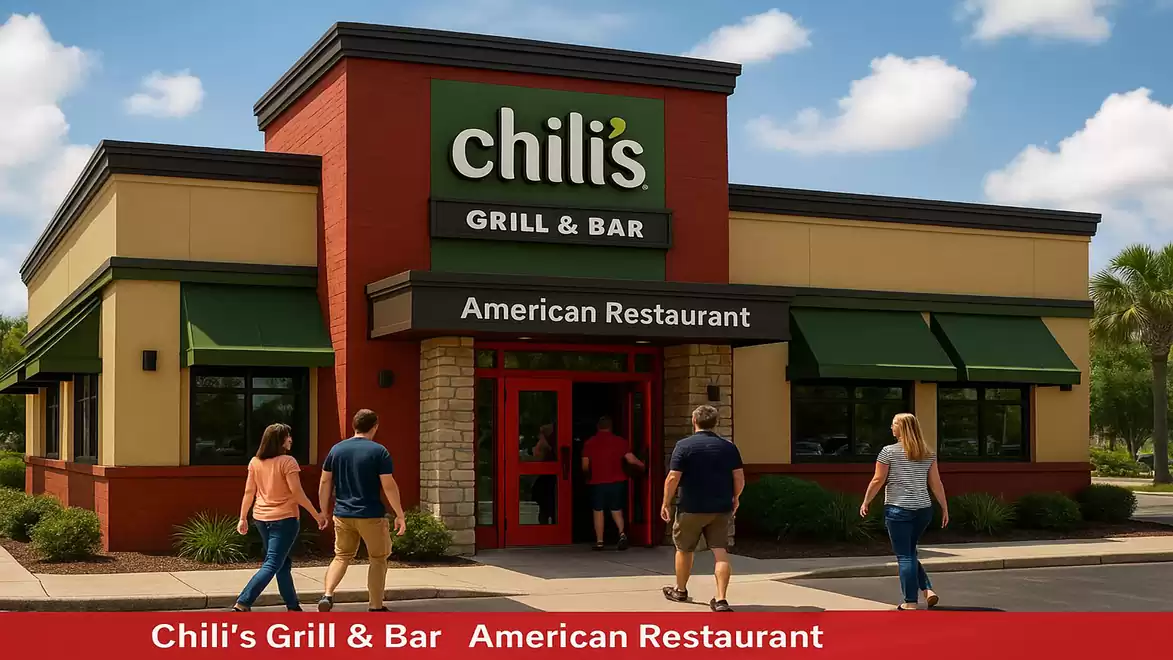 Image of a restaurant with the sign 'Chili's Grill & Bar'. Several people are walking towards the entrance of the building under a clear sky.