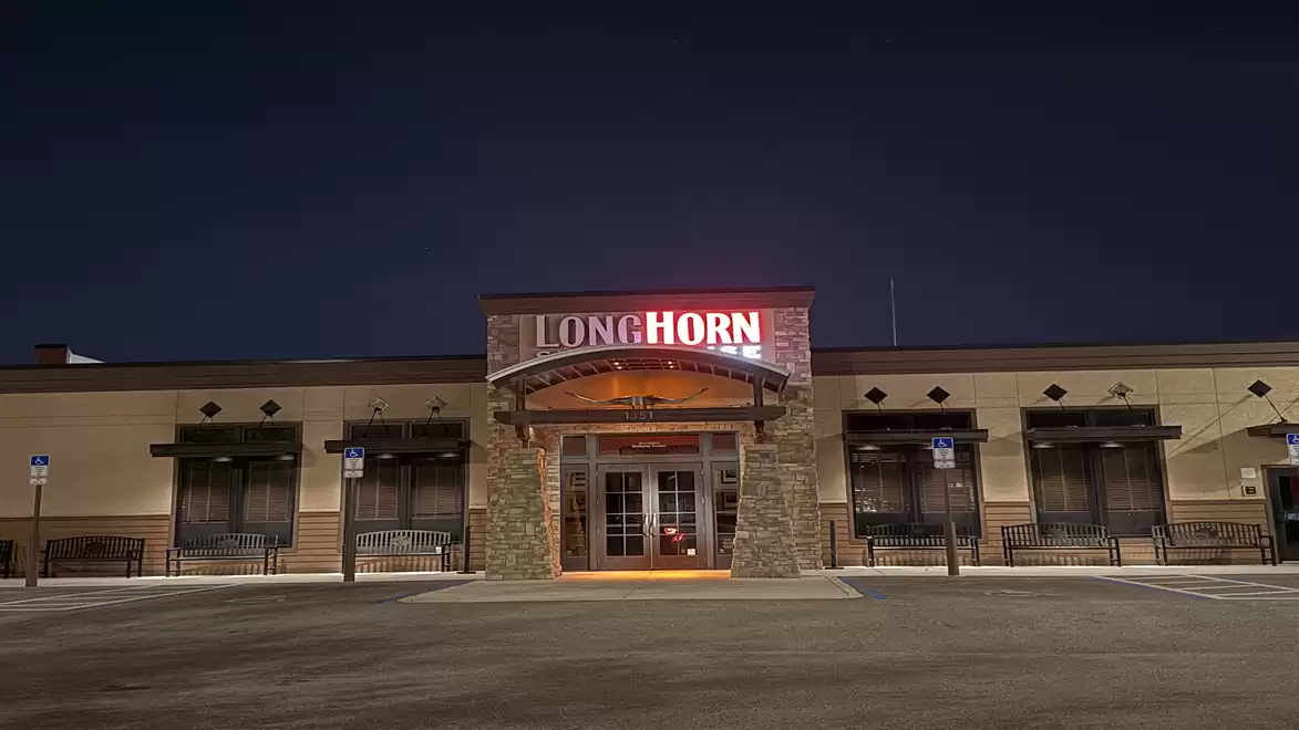 Exterior view of a Longhorn Steakhouse at night with illuminated entrance sign.