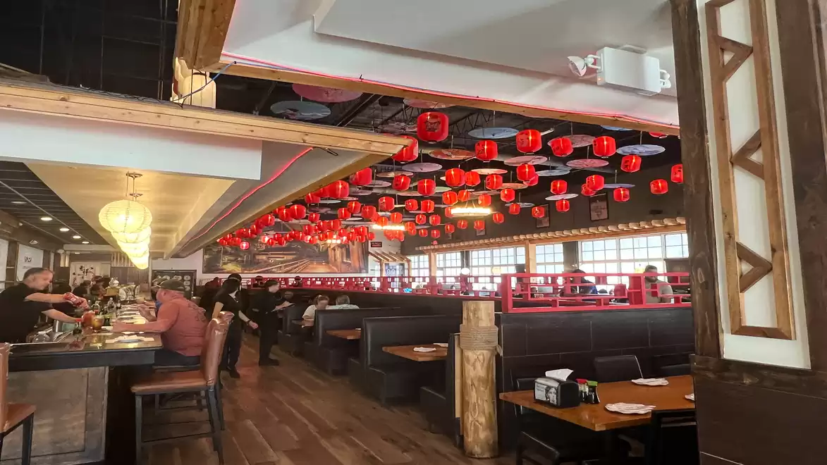 Interior view of a restaurant with red lanterns on the ceiling and multiple seating areas with drinks and guests.