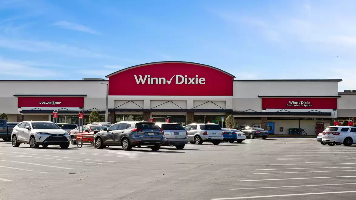 Large parking lot in front of a supermarket named Winn-Dixie on a sunny day.