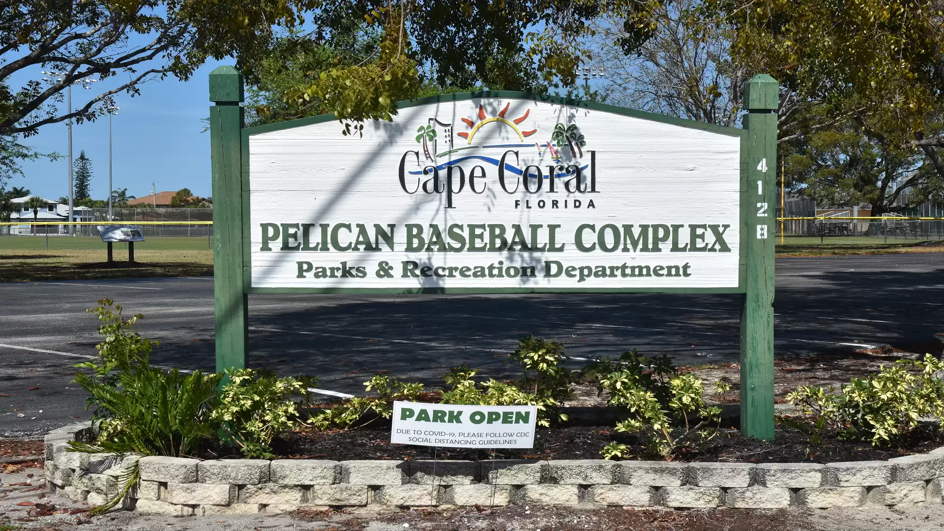 Entrance sign of Pelican Baseball Complex in Cape Coral, Florida, with surrounding landscape and a notice indicating the park is open.