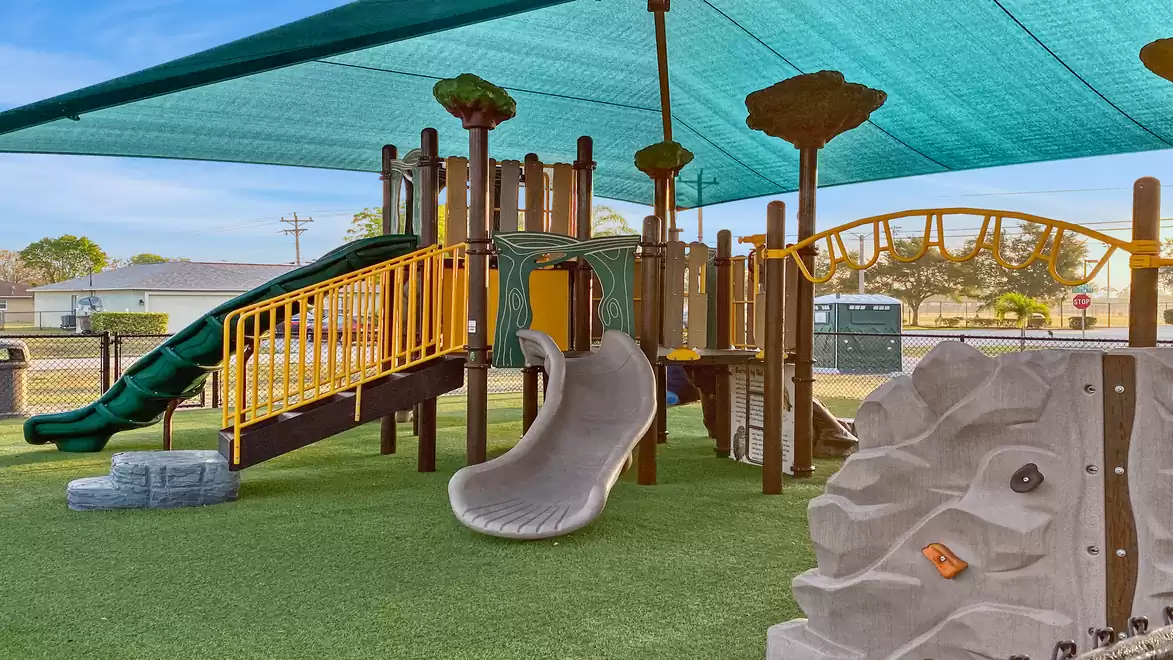 Modern children's playground with slide, climbing net and fabric shade roof.