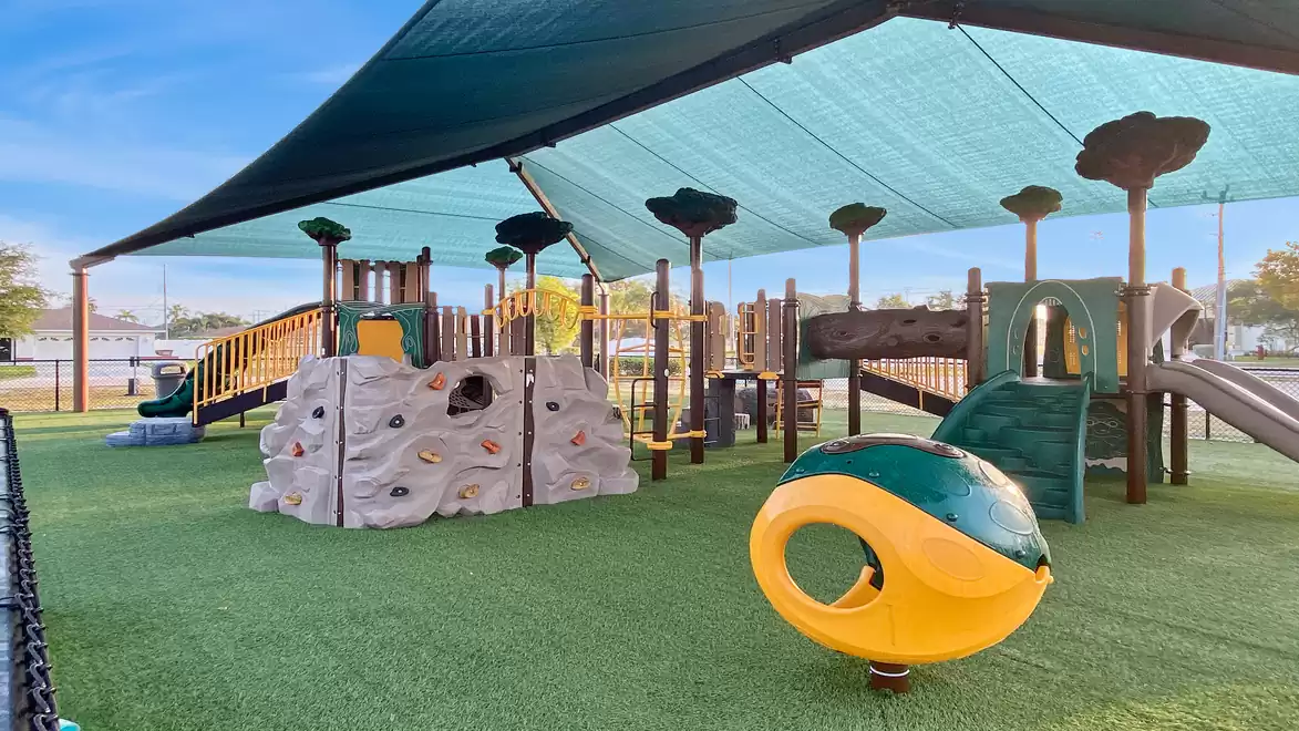 Modern playground with climbing wall, slides, and a sunshade.