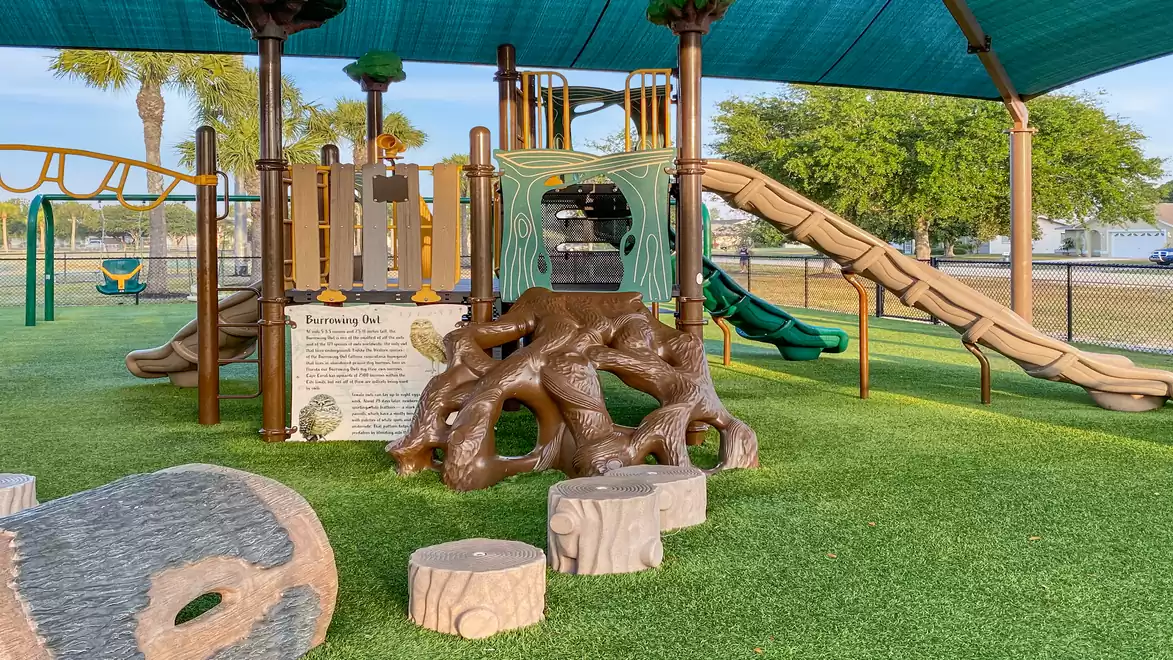 Outdoor playground with climbing structure and slide under sunshade
