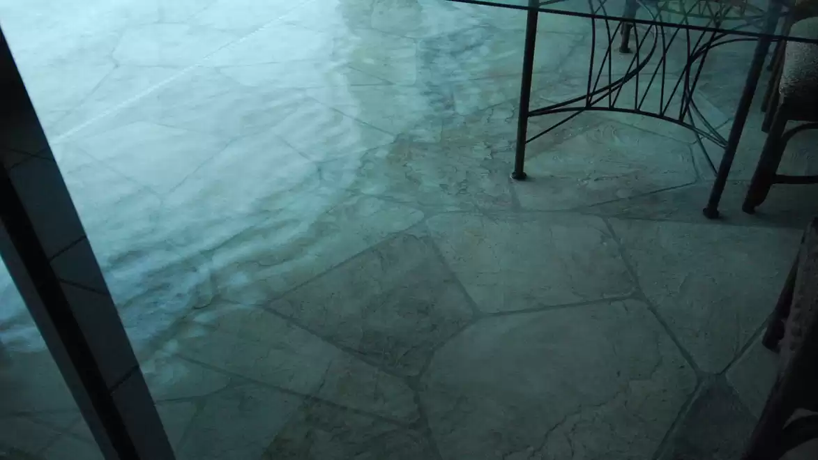 View of a terrace with tiled flooring and an overhanging table. In the background, water is visible slightly flooding the terrace.
