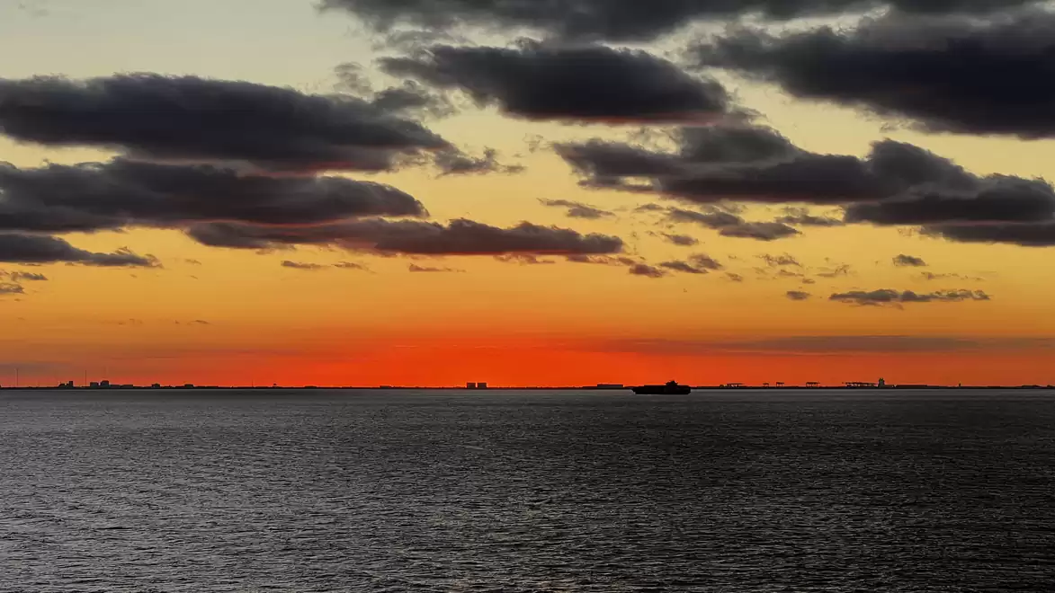 Dramatic sunset over the sea with dark clouds in the sky.