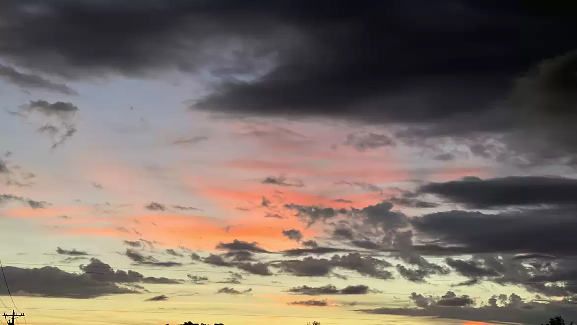 Dramatic sunset sky with dark and pastel-colored clouds.