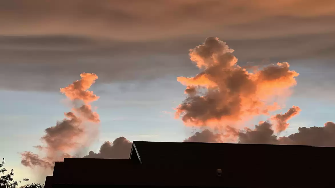 A sunset sky with striking orange cloud formations above the silhouette of buildings.