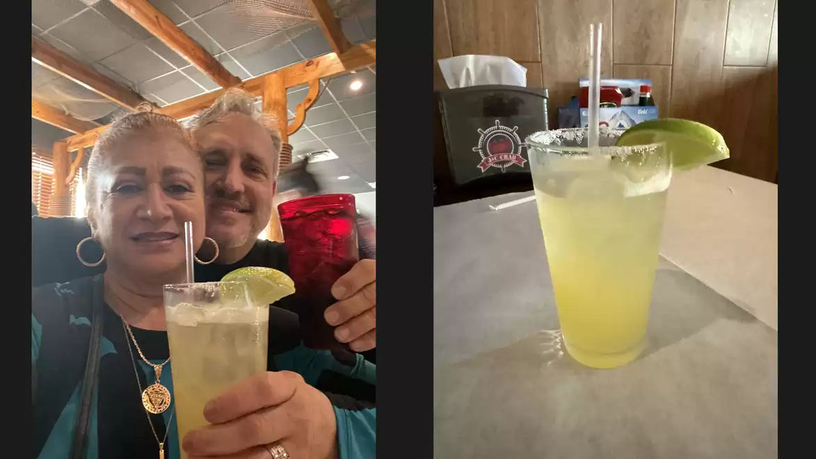 A couple in a restaurant holding drinks; left Margarita, right Margarita with lime slice.