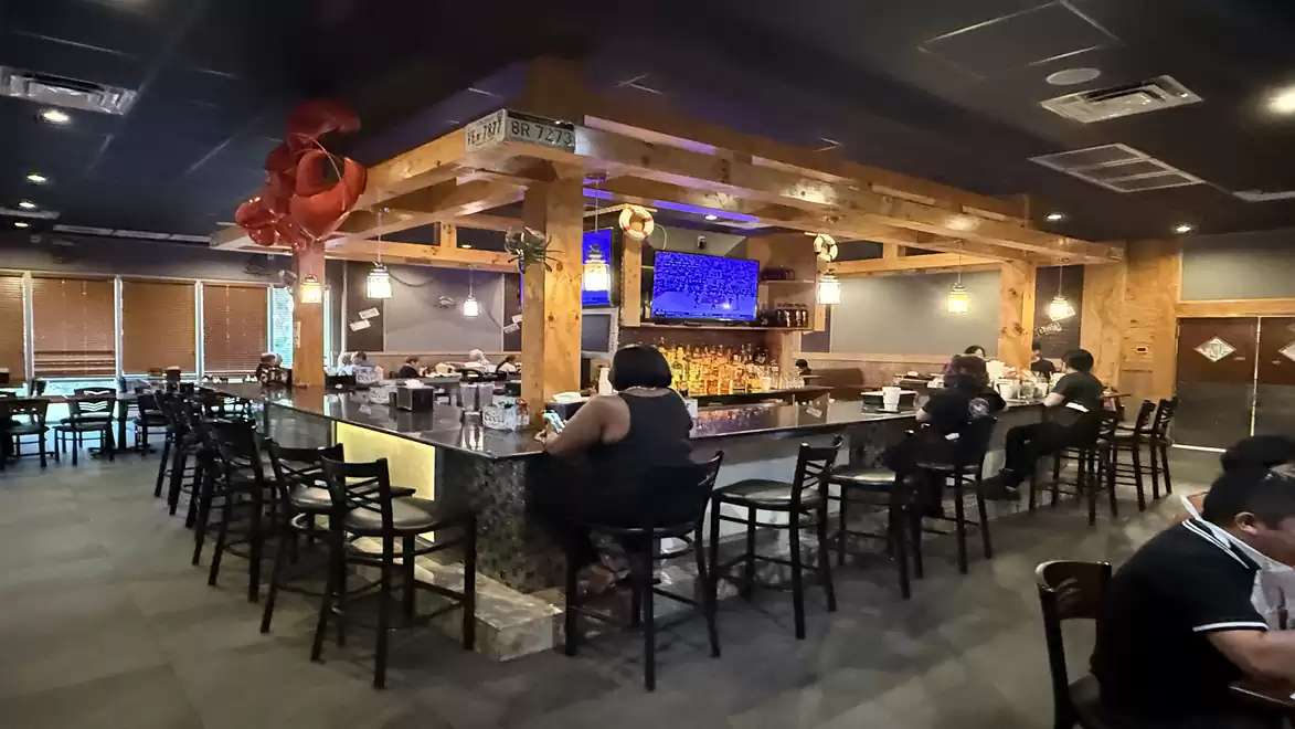 Cozy restaurant bar with wooden elements, several guests, and atmospheric lighting.