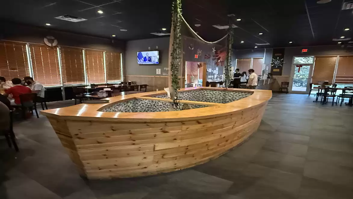 Interior view of a restaurant featuring an anchor-shaped wooden dining table in the center with modern furnishings.