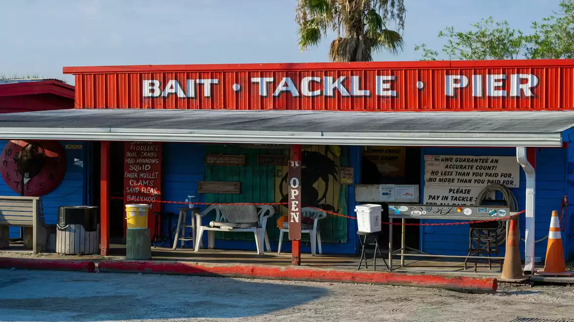 A colorful shop with the sign 'Bait Tackle Pier', offering fishing tackle and bait.