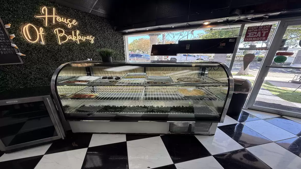 Interior view of a modern bakery with empty shelves and decorative lighting, black and white checkered floor.