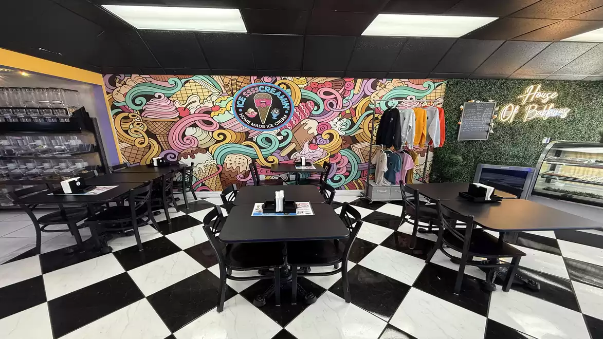 Colorful café interior with graphic wall art, black tables, and black-and-white checkered floor, along with a clothing display.