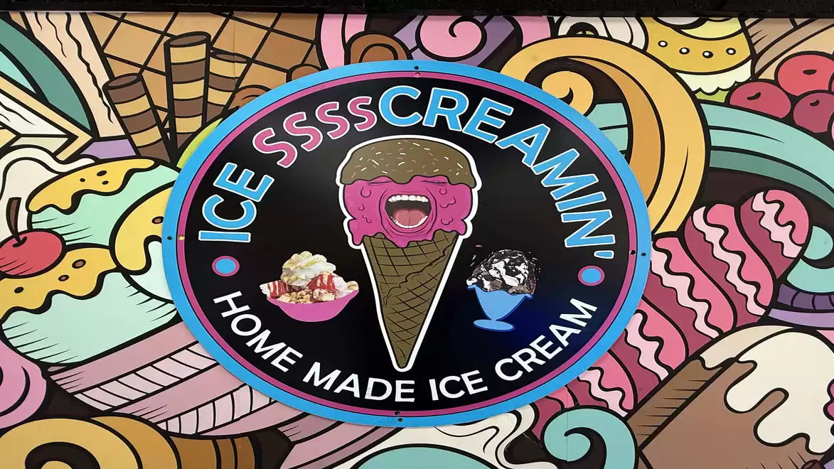 A colorful mural featuring an ice cream advertisement. In the center, a large logo with a smiling ice cream in a cone, surrounded by various dessert motifs.
