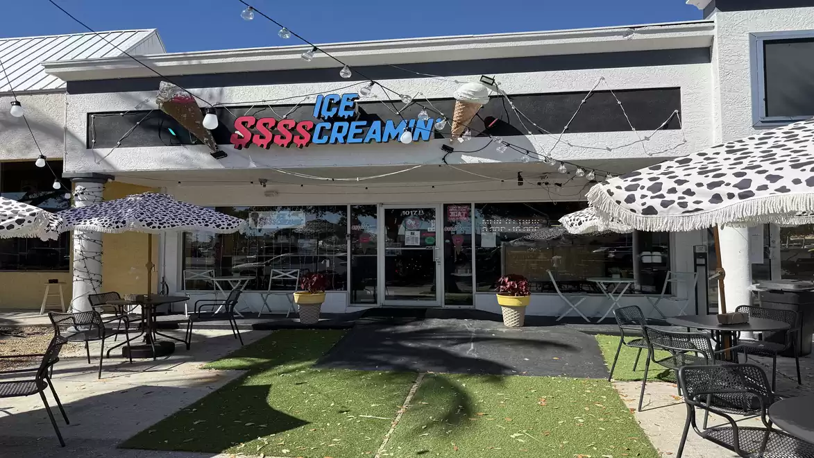 Exterior view of an ice cream parlor with decorative umbrellas and seating on a patio.