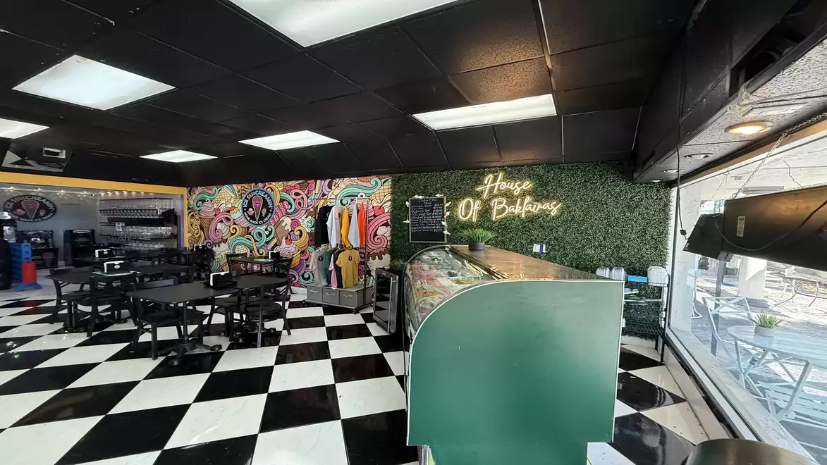A modern café with a black and white checkered floor, colorful wall art, and stylish lighting.