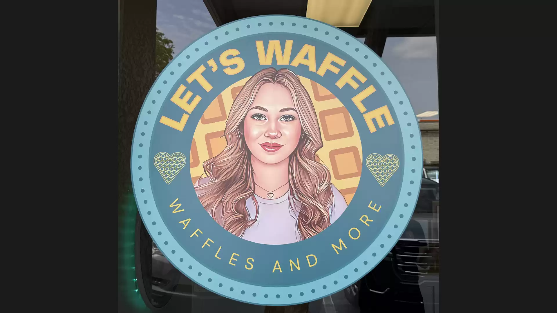 A round logo of a waffle shop with the text 'Let's Waffle' and 'Waffles and More'. The logo features a portrait of a smiling woman with long hair.