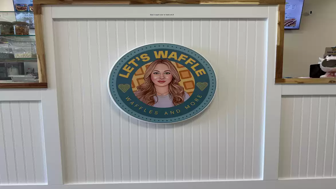 Wall with 'Let's Waffle' logo in a café featuring a drawing of a woman.
