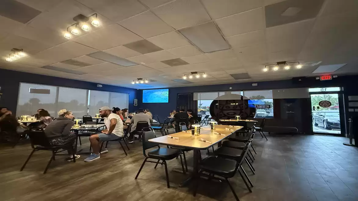 A modern restaurant with several set tables and guests seated inside.