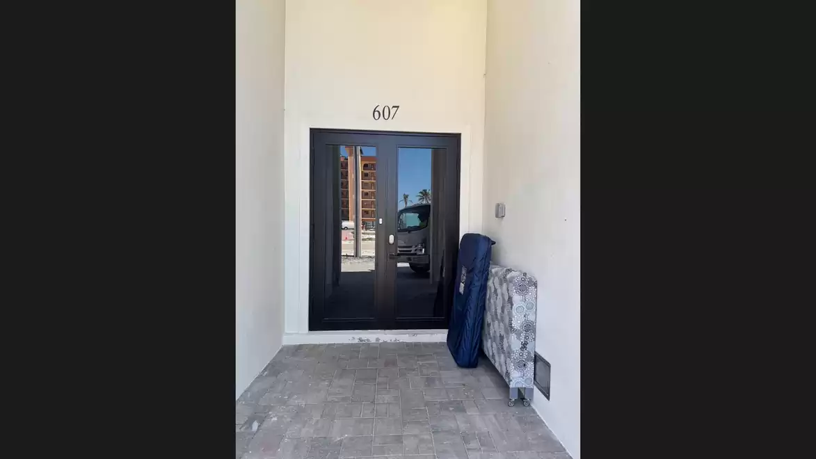 Entrance door with number 607, next to which items are placed against the wall.
