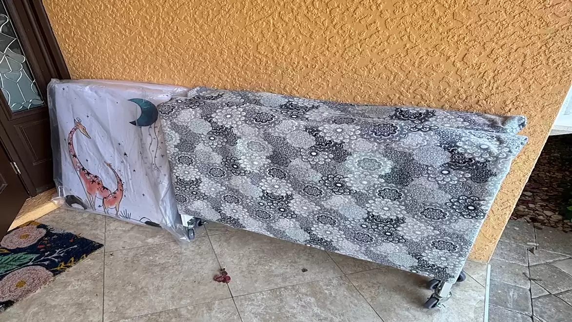 Two folded beds are placed on a terrace. The right bed is covered with a patterned blanket, while the left one shows a fish and a moon on a white cover.