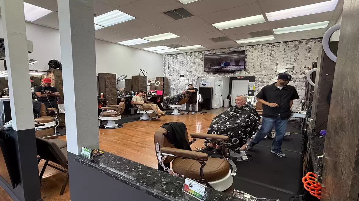 Interior view of a modern barber shop with several customers and barbers.