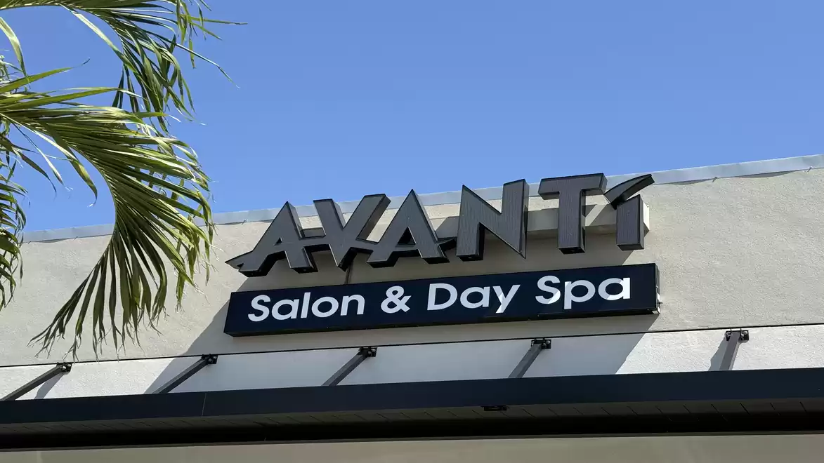 Exterior view of a building with the sign 'Avanti Salon & Day Spa' and a palm tree in the foreground.