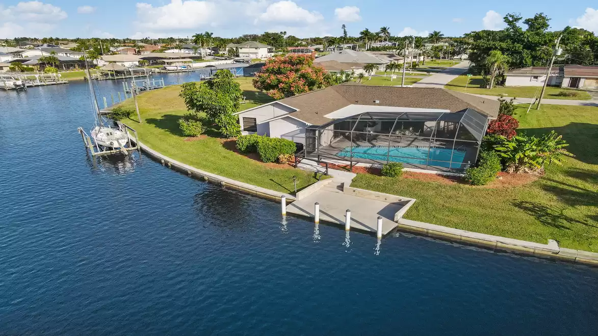 Villa Belle Paradise - Aerial view of a house with a pool and boat dock by the water in a residential area.