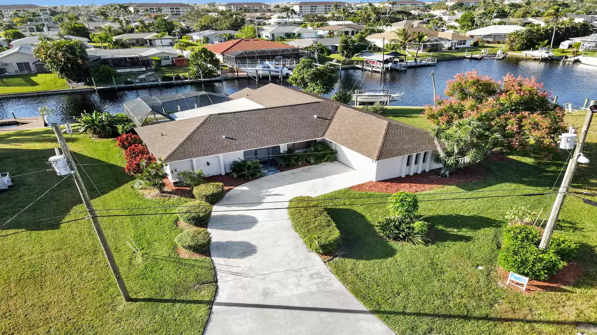 Villa Belle Paradise - Aerial view of a large house with a garden and paved driveway, with a canal and boats in the background.